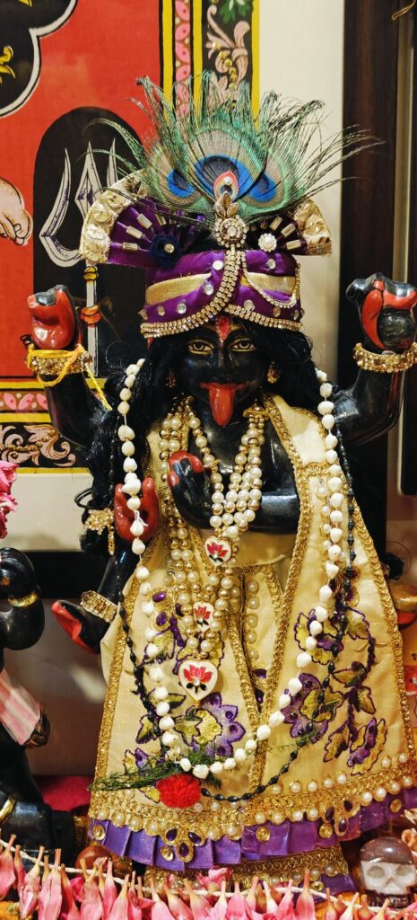 Deity adorned with Shri Krishna shringar, pearl garlands and a peacock-feather crown for Janmashtami